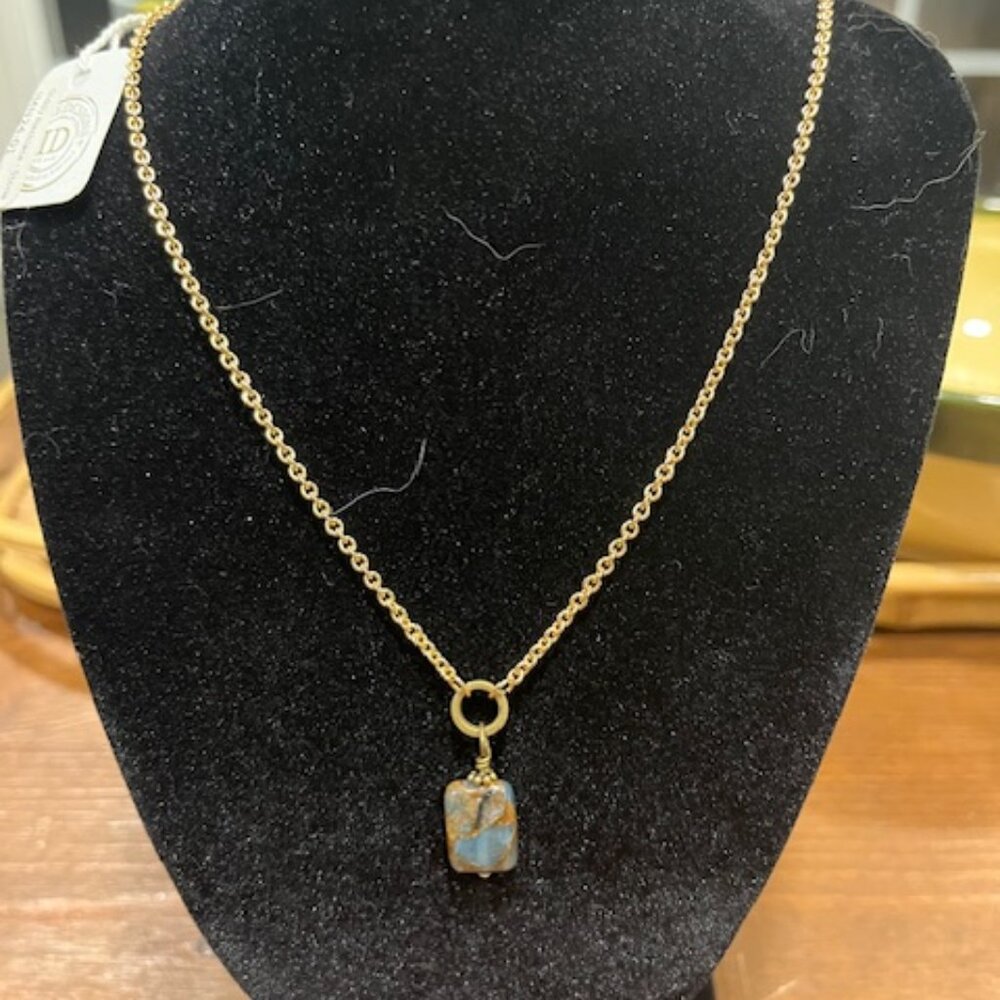 A modern gold-toned chain necklace with a raw crystal pendant.